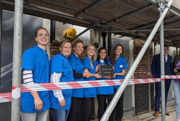 Zes medewerkers van het zorgteam leggen eerste steen