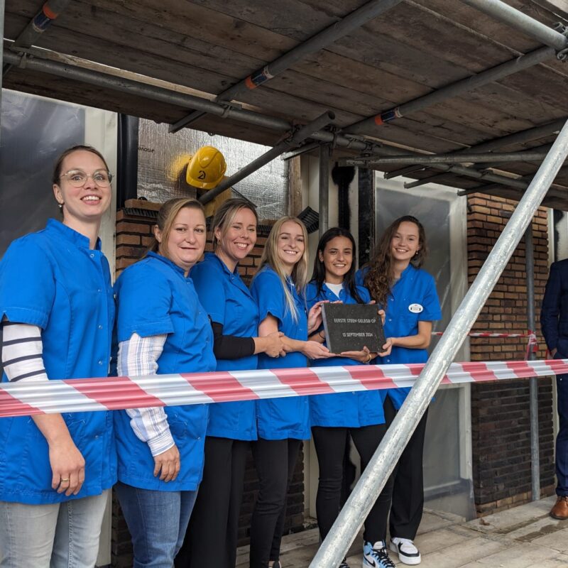 Zes medewerkers van het zorgteam leggen eerste steen